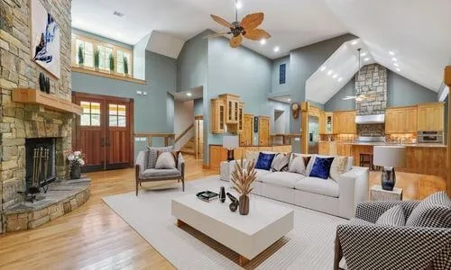 Great room with a stone fireplace, vaulted ceiling, wood floors and an open kitchen